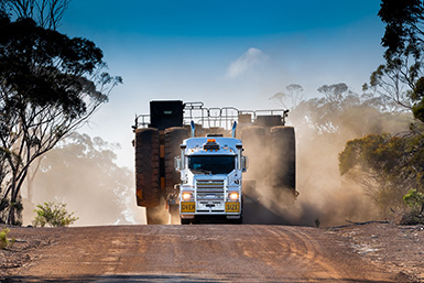 Oversize truck hauling a dump truck.